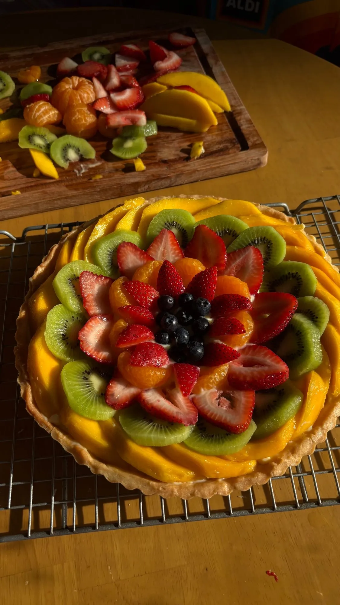 Fruit tart decorated in a rosette of strawberries, kiwi, mango, mandarin, and blueberries