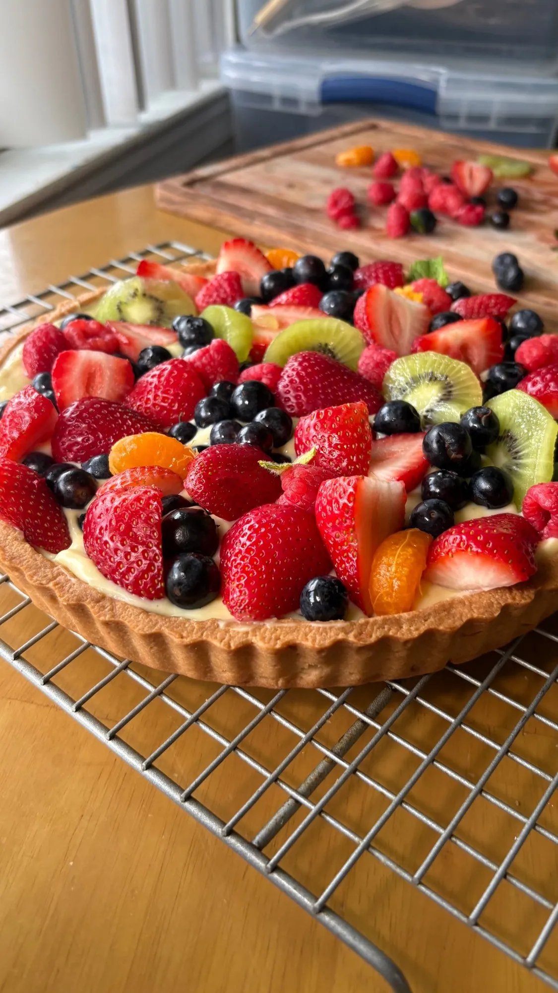 Close view of a fruit tart with strawberries, blueberries, kiwi, and mandarin on pastry cream